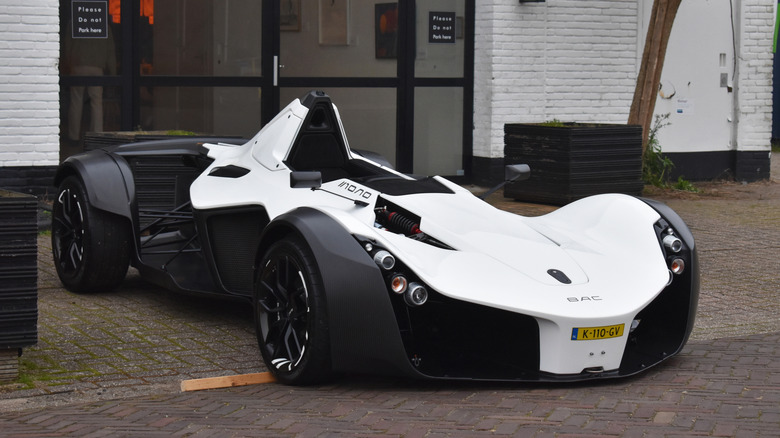 A white BAC Mono sits parked outside.