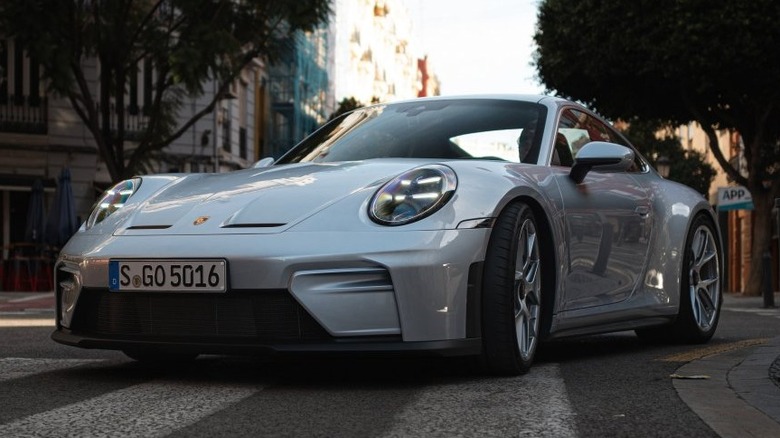A light gray Porsche GT3 Touring on a road in the city