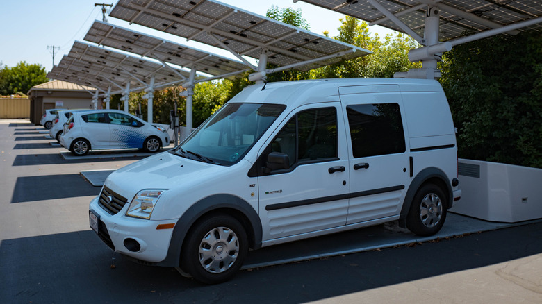 A Ford Transit parked under a shaded solar awning.