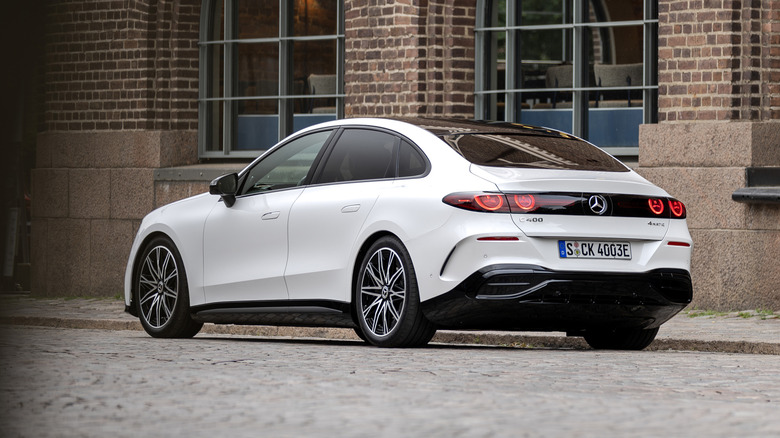a white electric Mercedes-Benz C-Class parked in front of a brick building