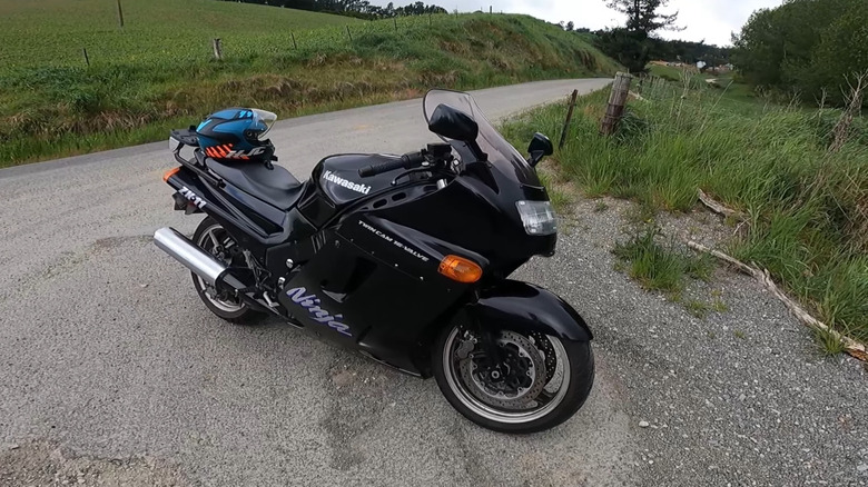 A gloss black Kawasaki Ninja ZX-11 sport-touring motorcycle parked on a gravel roadside turnout.
