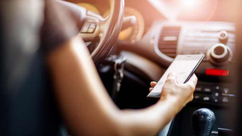 Close up of someone operating a cellphone in a car