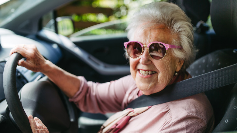 Older woman in sunglasses at the wheel of a car