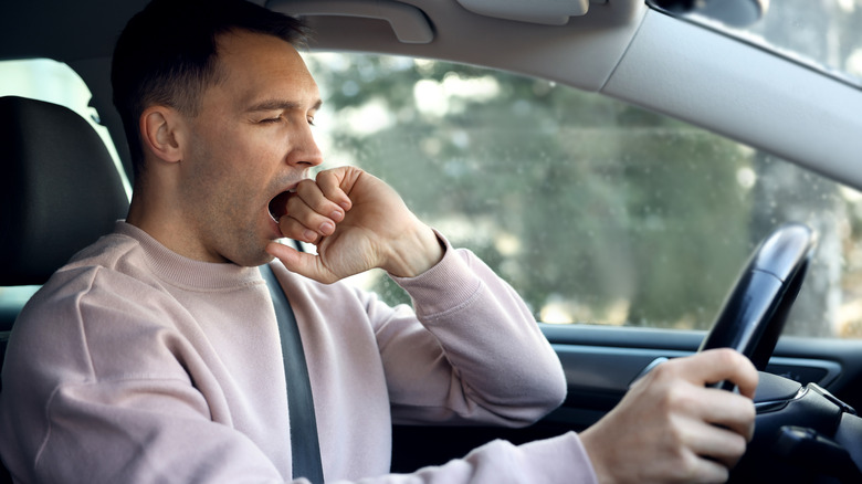 Yawning male driver at wheel of a car